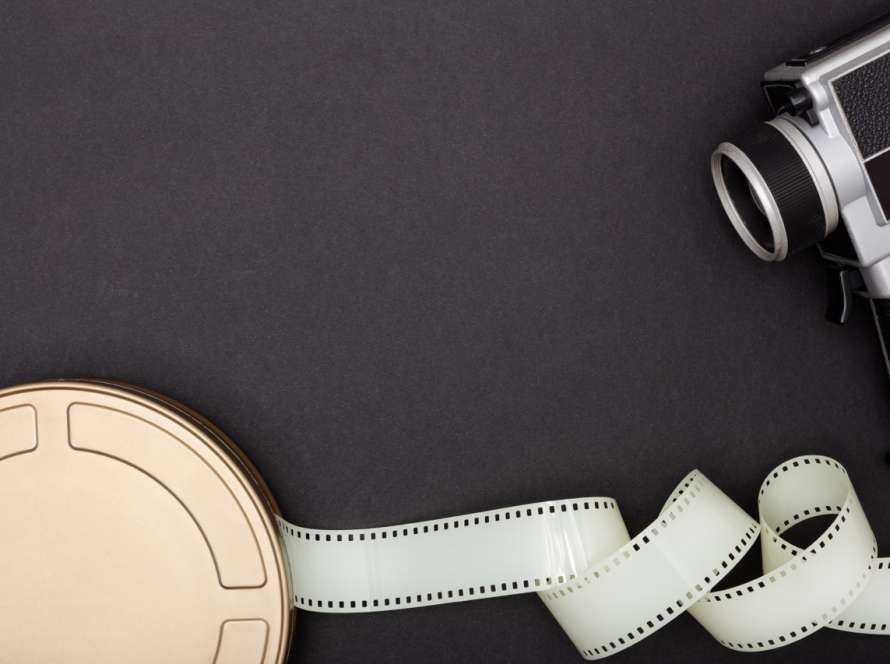 Motion Picture Film Can, film camera and film strip on black background. Movie or TV background. Top view Copy space